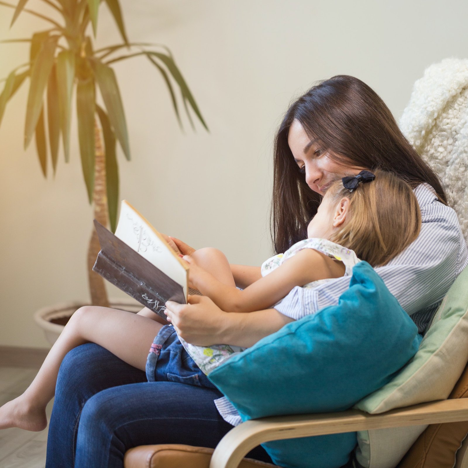 Mother with a little girl reading a book together in the house